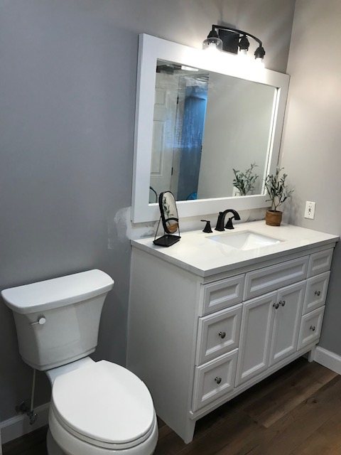 Bathroom remodel with a white vanity, framed mirror and black fixtures
