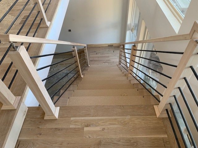 Wide oak staircase with modern horizontal metal railing