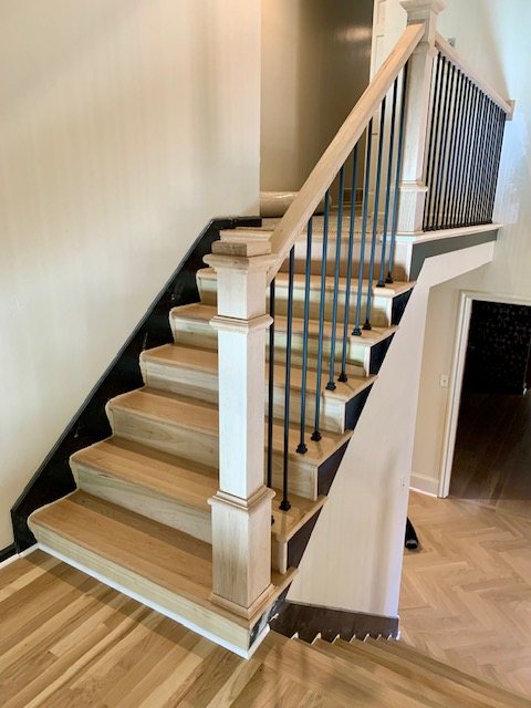 Remodeled staircase with oak treads, a boxed newel post and black iron balusters