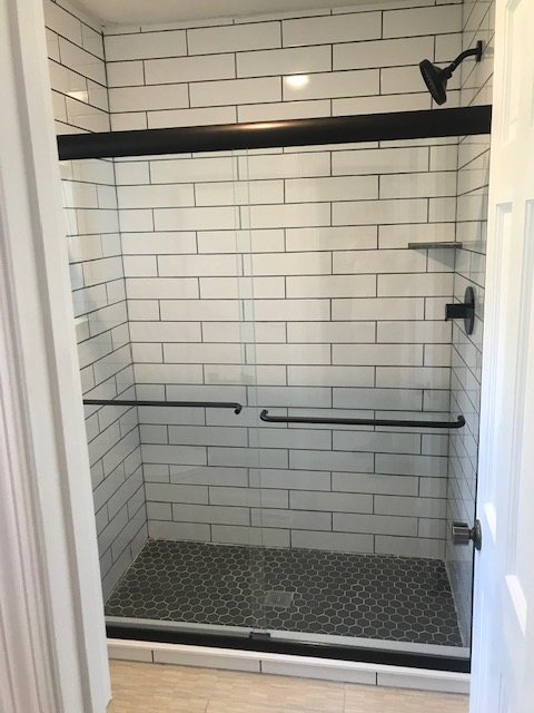 Walk-in shower with white subway tile, black fixtures and a glass door